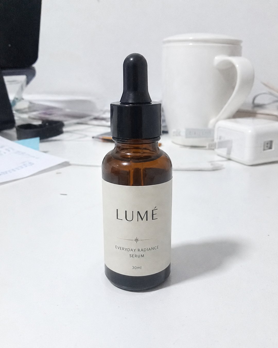 LUMÉ serum — ordinary phone snapshot on a cluttered desk